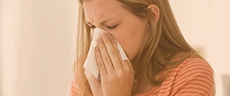 woman with sinusitis blowing nose