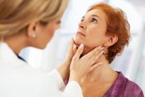 doctor examining a patient's thyroid 