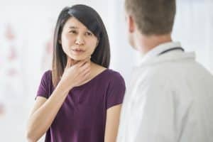 A woman is at a check-up at the doctors office. She is talking to the doctor about a cold.