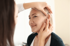 Otolaryngologist putting hearing aid in woman's ear on