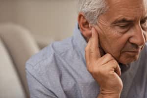 Side view of senior man with symptom of hearing loss. 